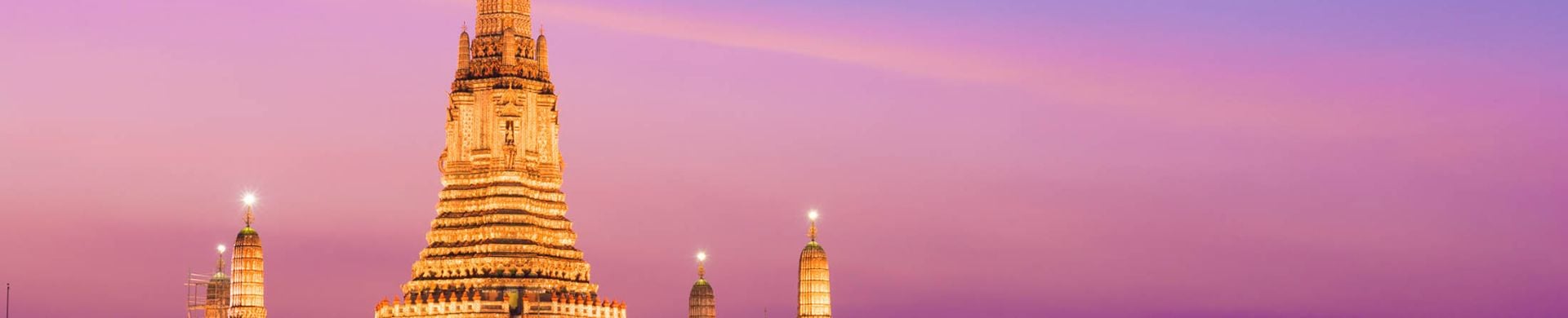 The illuminated temple of Wat Arun on the Chao Phraya river at sunset in Bangkok, Thailand