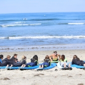 Group of teens receiving surfing lessons on the beach in San Diego